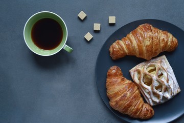 Cup of coffee and croissants on dark background 