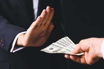 Businessman refusing to take bribe against dark background, closeup