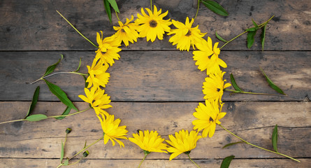 A Circle of yellow daisies on a wooden table
