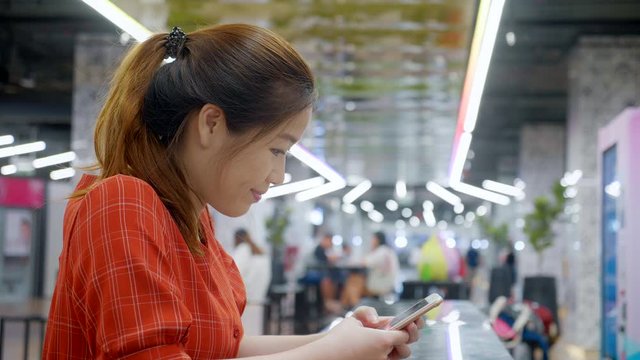 Portrait of asian woman using smartphone chatting with friends in public 