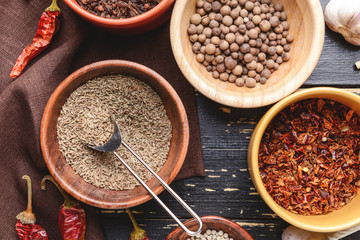 Bowls with different dry herbs and spices on wooden background