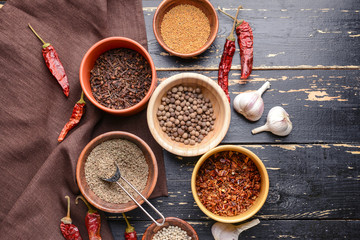 Bowls with different dry herbs and spices on wooden background