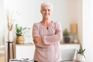 Confident senior woman posing over workplace at home