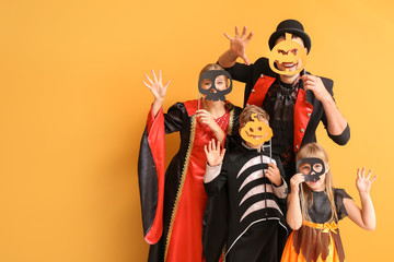 Family in Halloween costumes on color background