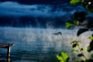 dark fog and  boat in the fog on a lake in the mountains