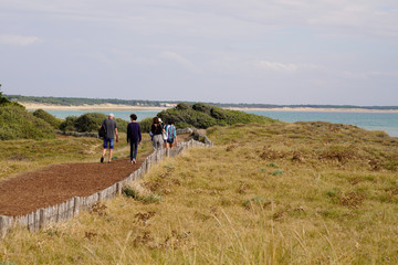 family back view behind walk path in St Vincent sur Jard in Vendée seacoast