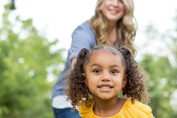 Mother and daughter laughing and playing at the park.