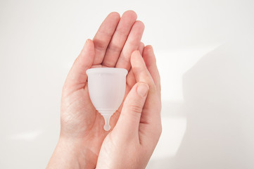 Eco-friendly hypelergenic gynecological silicone menstrual cup for women. Hygienic silicone bowl for collecting menstrual blood in the hands on a white background. Save money.