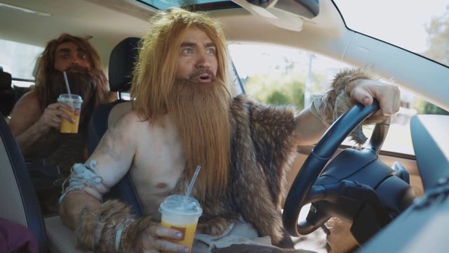 Neanderthal caveman holding takeaway juice growling enjoying driving car modern transportation in city. Urban wildlife. Human evolution.