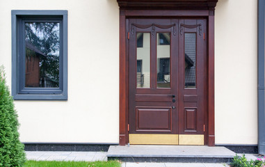 The original entrance door and window on the background of a bright house