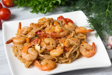 Pasta with shrimp, tomatoes and herbs on the plate.