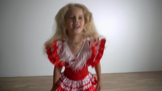 Blond girl child jump and dance with fashionable dress. Gimbal movement up shot.