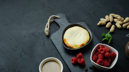 Mały sernik z malinami, orzechami i kawą. Czarne tło, widok z góry.