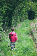 petite fille habillée en rose sur un chemin à la campagne au printemps