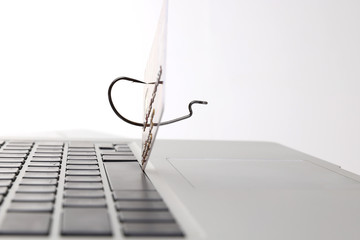 The Bank card on the fishing hook lies on the keyboard of the laptop. The concept of money fraud on the Internet