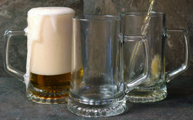Pouring beer into traditional beer steins on black slate bar table..