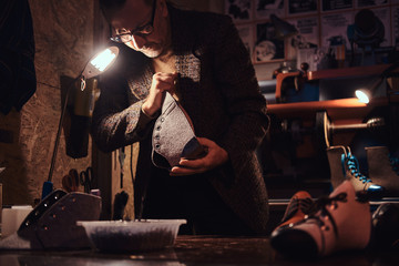 Elderly person is serving boot service at his own personal workshop.