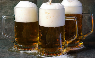 Pouring beer into traditional beer steins on black slate bar table..