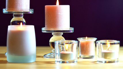 Aromatherapy composition with pink candles on table against purple background, shallow focus close up.