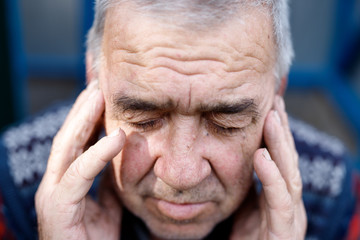 Fototapeta premium Depressed old man hiding his face behind hands. Adult man has a headache.