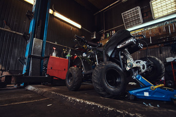 ATV with broken wheel at auto service workshop is waiting to be fixed.