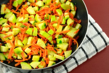 Sauteed stir fry zucchini carrots and green onions in frying pan on dish towel