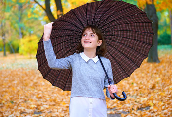 teen girl posing with umbrella and autumn leaves in city park, outdoor portrait