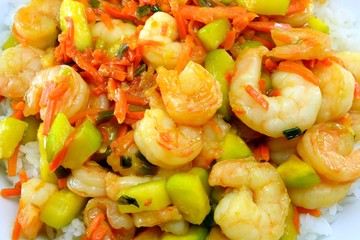 Close up of stir fry shrimp, zucchini and carrots dish on rice