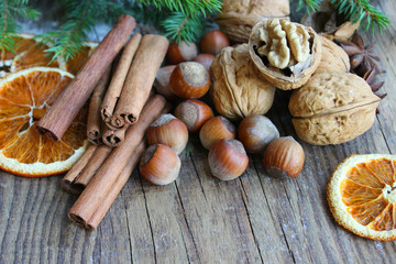 Christmas decor. Christmas spices. Cinnamon sticks, anise stars, walnuts, hazelnuts, dried orange on an old wooden background, copy space.