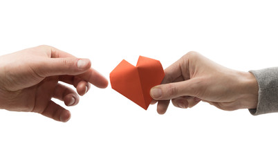 Obraz premium Red heart in woman and man hands. Image on isolated white background. Concept of love, giving gifts, donorship.