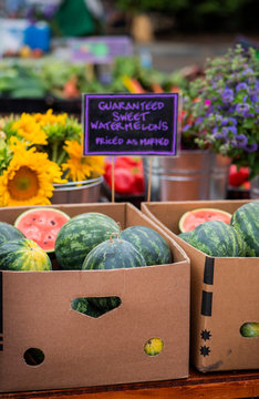 Small Watermelons In Boxes At Farmers Market, Whole And Cut Pink And Green Melon, Handwritten Sign 