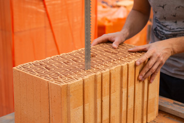 Bricklayer is cutting a brick with an electrical saw