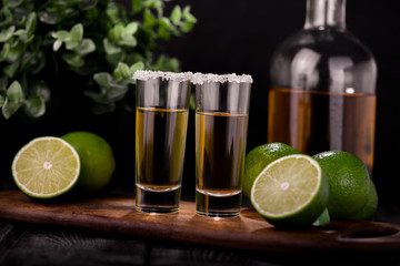 Mexican Gold Tequila with lime and salt on black background with copyspace.