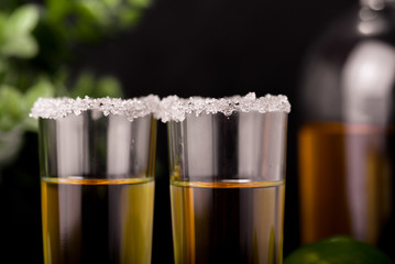 Mexican Gold Tequila with lime and salt on black background with copyspace.