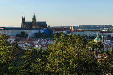 Fototapeta na wymiar Panoramic view of Prague Castle with the St. Vitus Cathedral above the rooftops of the district Mala Strana from the viewpoint Petrin with blue sky and sunshine