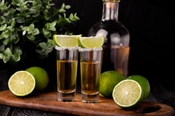 Mexican Gold Tequila with lime and salt on black background with copyspace.