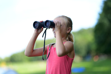 Petite fille regardant à travers des jumelles en plein air