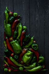 variety of peppers flat lay, harvest from the garden on dark wooden table,  food blog, copyspace, red and green peppers, ancho, shishito, bell peppers, anaheim, arranged in a tight cluster 