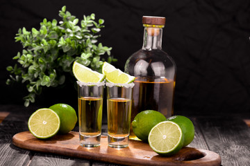 Mexican Gold Tequila with lime and salt on black background with copyspace.