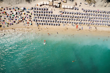 Fototapeta na wymiar Aerial view of sandy beach with tourists swimming in beautiful clear sea water and yacht from top view.