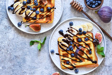 Vanilla waffles with chocolate sauce with peaches and berries on a kitchen stand. View from above.