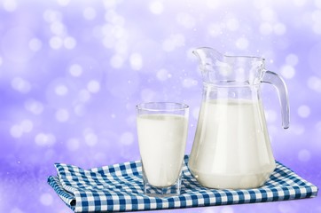 Glass of milk and jug on blurred background