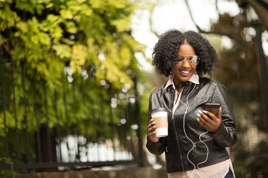 African American Woman texting and drinking coffee.