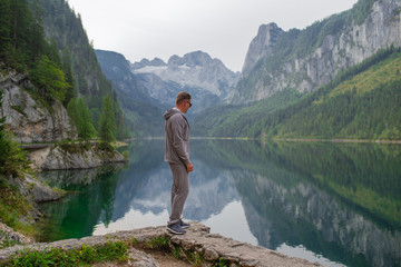 Naklejka premium Young sports guy enjoys the beauty on the lake in the mountains