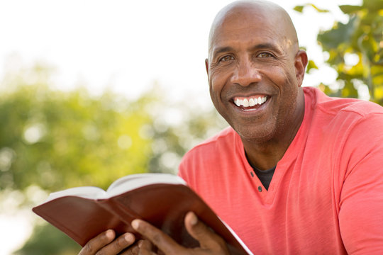 African American man praying and reading the Bible.