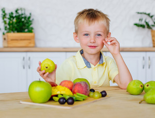 Fototapeta premium Happy little boy eating fresh fruits