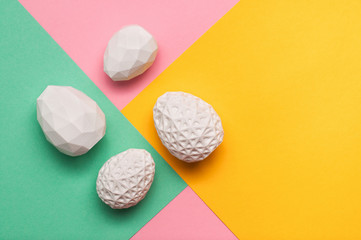 White Easter eggs with geometric patterns on color blocks background