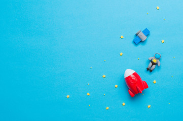 Spaceship, rocket, astronaut toys on blue background with copy space
