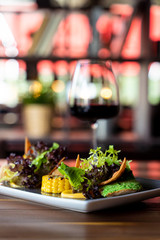 Side view of gourmet healthy snack with mixed greens, nachos, roasted chicken breast and grilled corn on blurred background