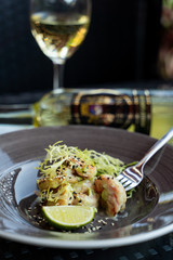 Close up of deep fried prawns with greens and a glass of white wine